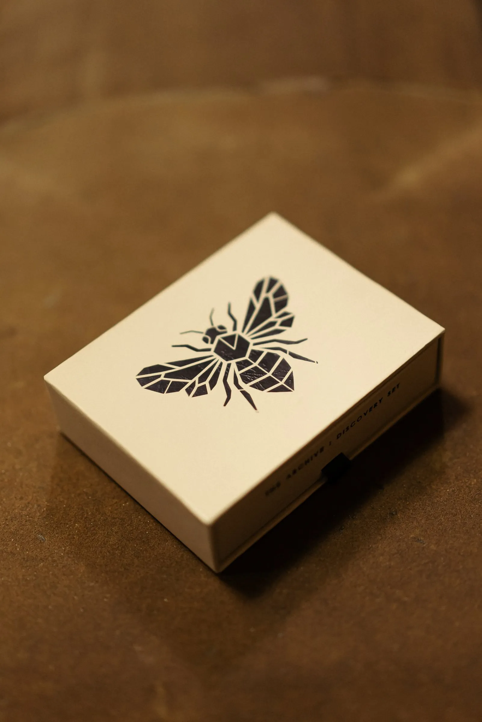 The Archive discovery set: a linen-wrapped drawer box stamped with the geometric bee mark.
